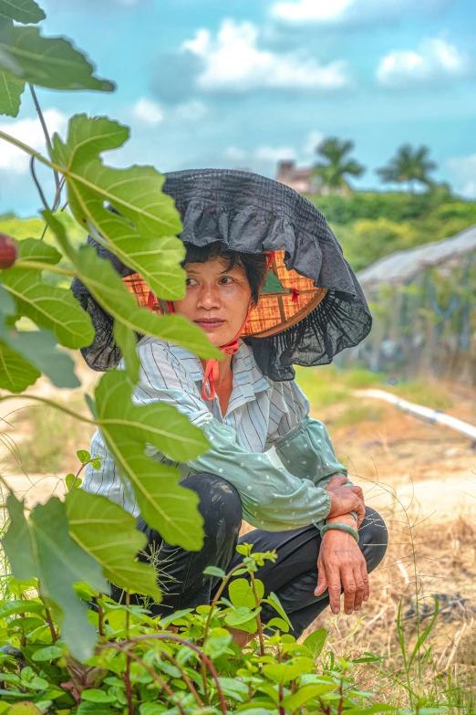 an old lady sitting in the grass with a black umbrella