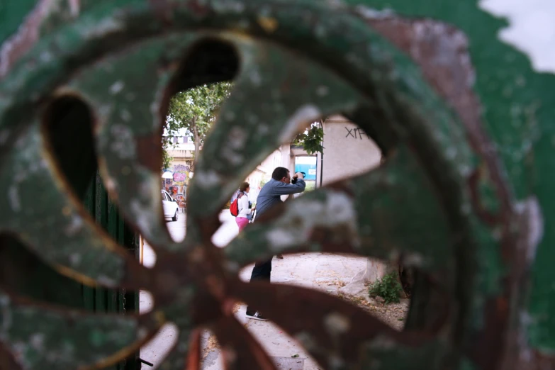 a po of a man sitting behind an iron gate