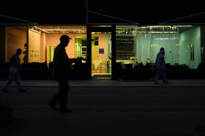 people walking in front of a building lit up at night