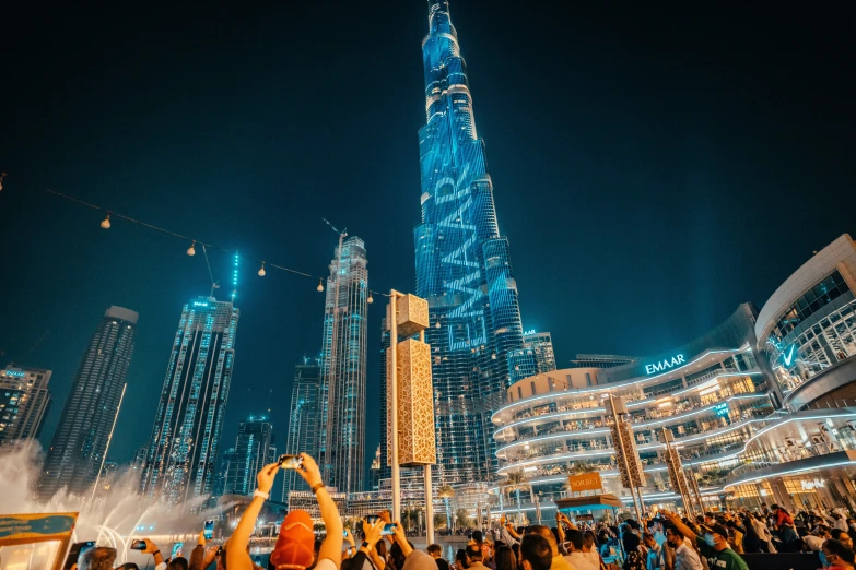 people dancing in the fountain in front of a very tall building