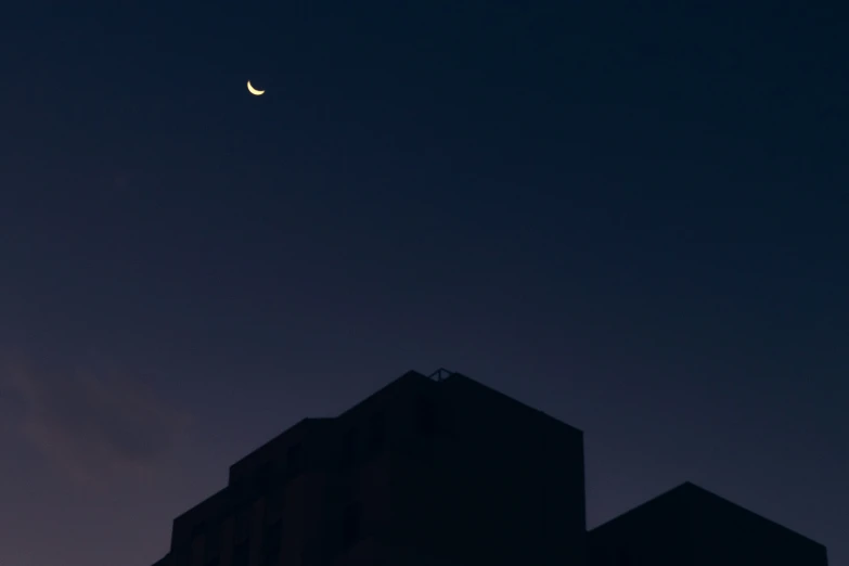 a cityscape of buildings with the moon above