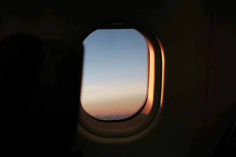an airplane window that is opened with a sunset