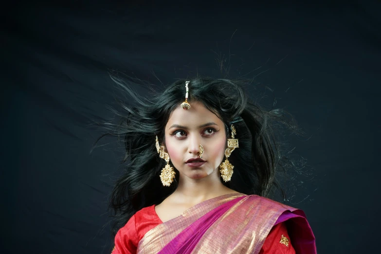 a small girl with a head piece in a sari
