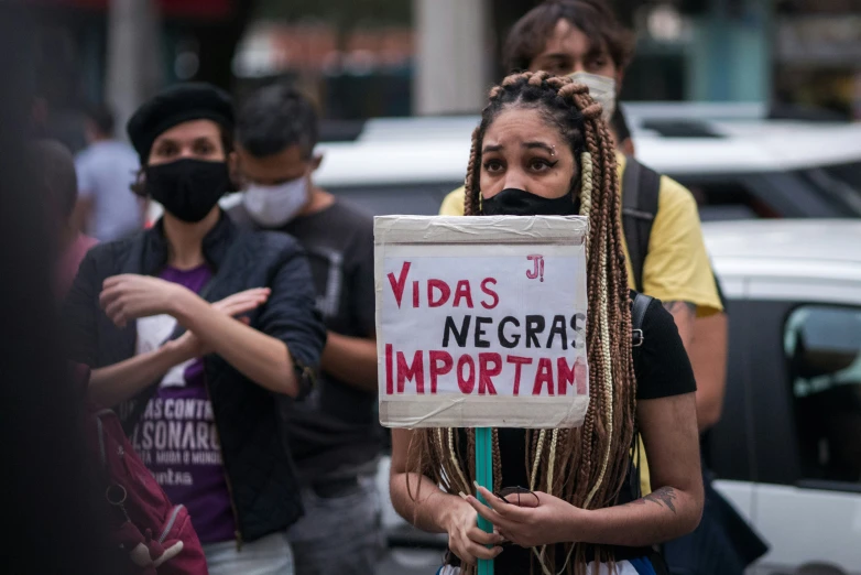 a woman wearing a mask with a sign that reads vidals negrat important