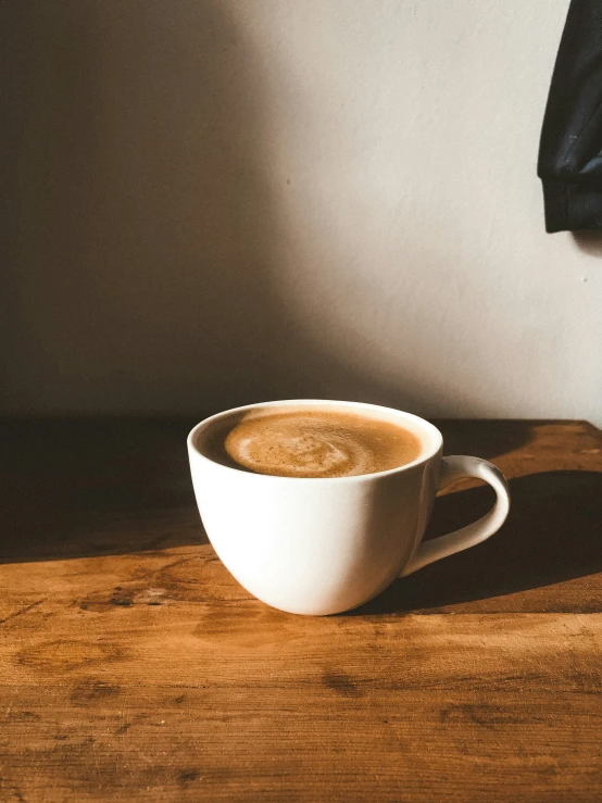 a cup of coffee sitting on a table next to a coat