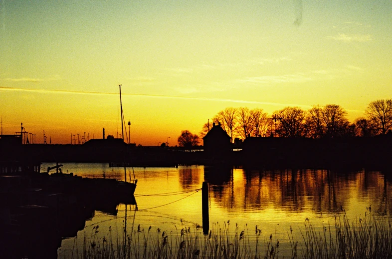 the sun sets on a lake with a house by it