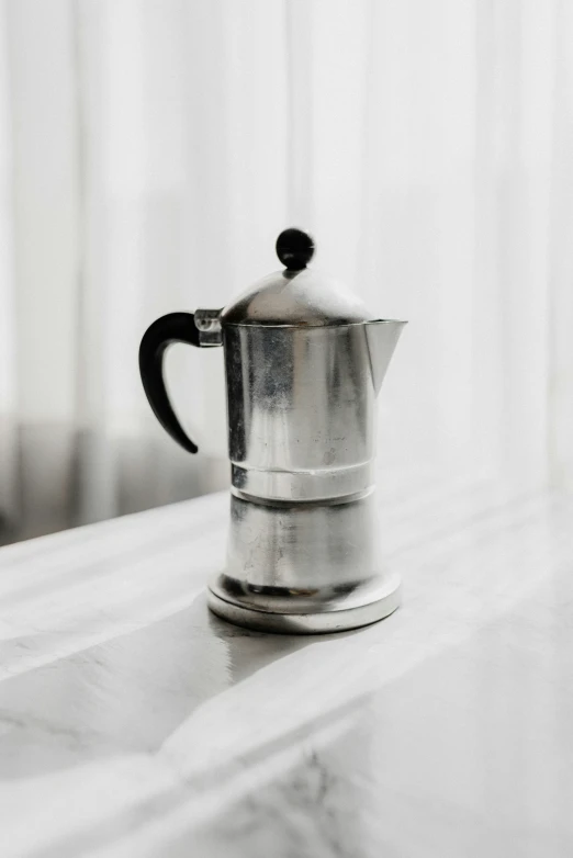 a silver and black metal coffee pot on a counter