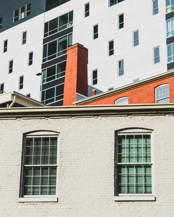 a building with two windows and red brick is next to a white and grey building