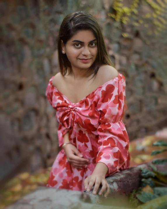 a woman leaning on a wall wearing a red dress