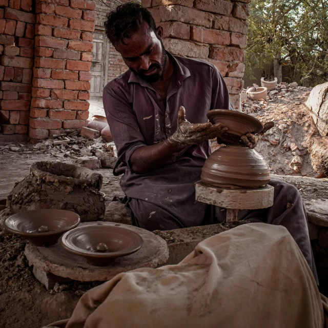 a man with glasses on, working on clay