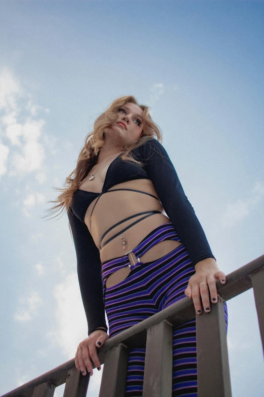 a woman wearing black top and colorful skirt standing near railing