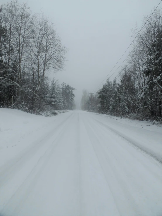 the road has snow on it and no cars are driving on it