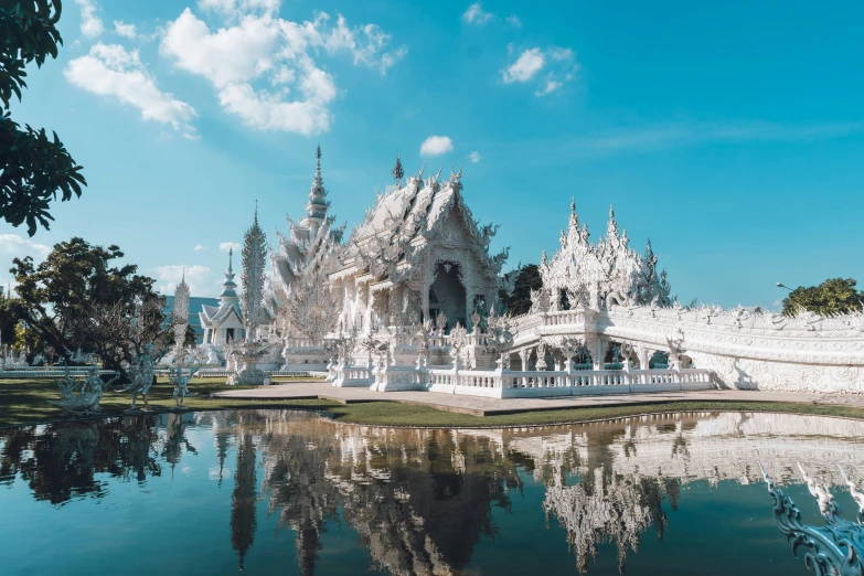 a white temple sits over the water