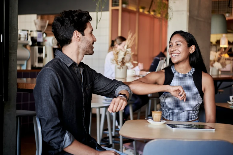 two people are sitting at the bar, one smiling and the other arm in hand