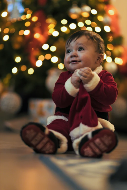 a baby in front of a christmas tree