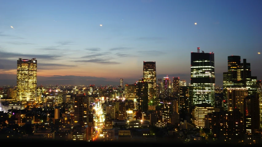 city buildings are shown at night as seen from the top of a hill