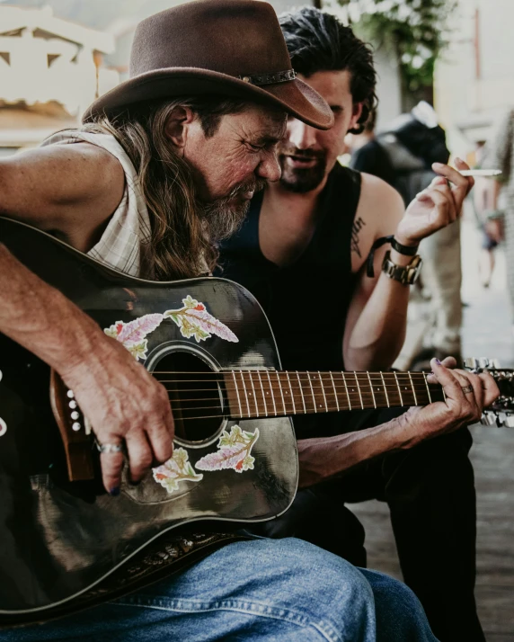 one man is holding a guitar in front of his other