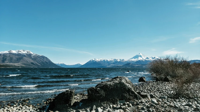 rocky shoreline with mountain peaks in the background