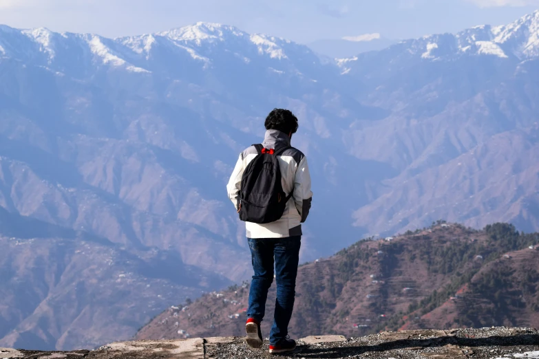 a man on the top of a mountain looking out into the mountains