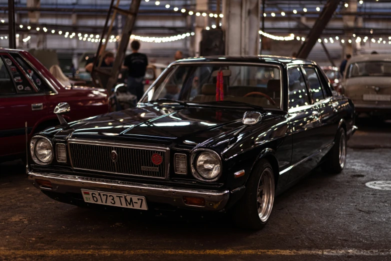 a very fancy black sedan parked in a big warehouse