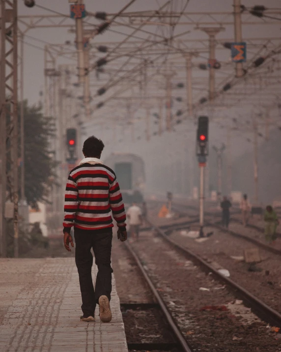 a young man walks across the railroad tracks