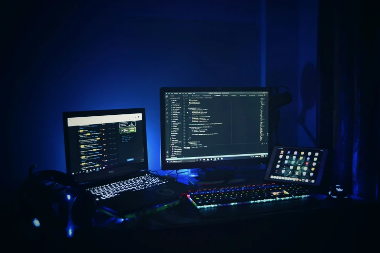 a computer and two laptops sitting in front of a computer screen