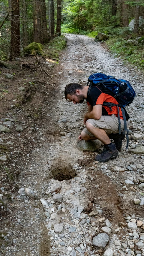 a man crouches down to take pictures while trekking