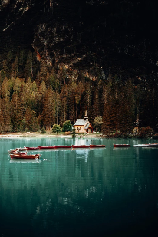 several boats floating on the water near the mountains