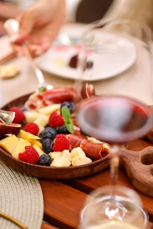 a tray of fruit and cheese and some wine on a table