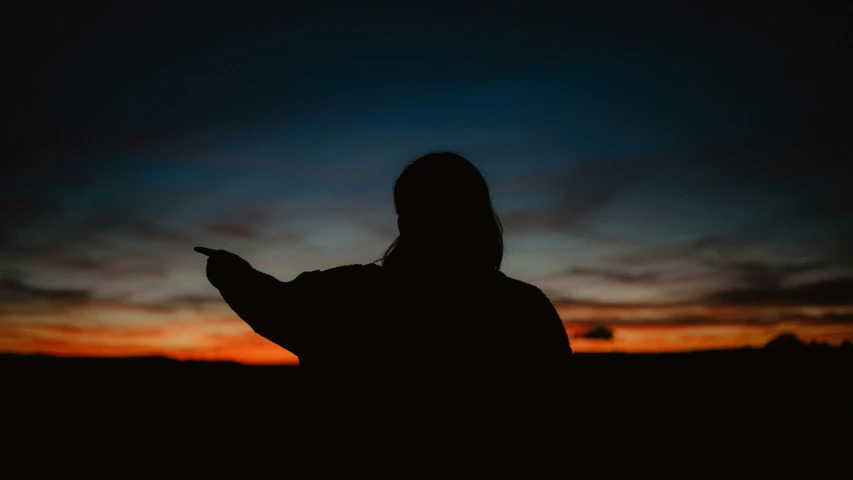 a woman with a cell phone standing on a hill