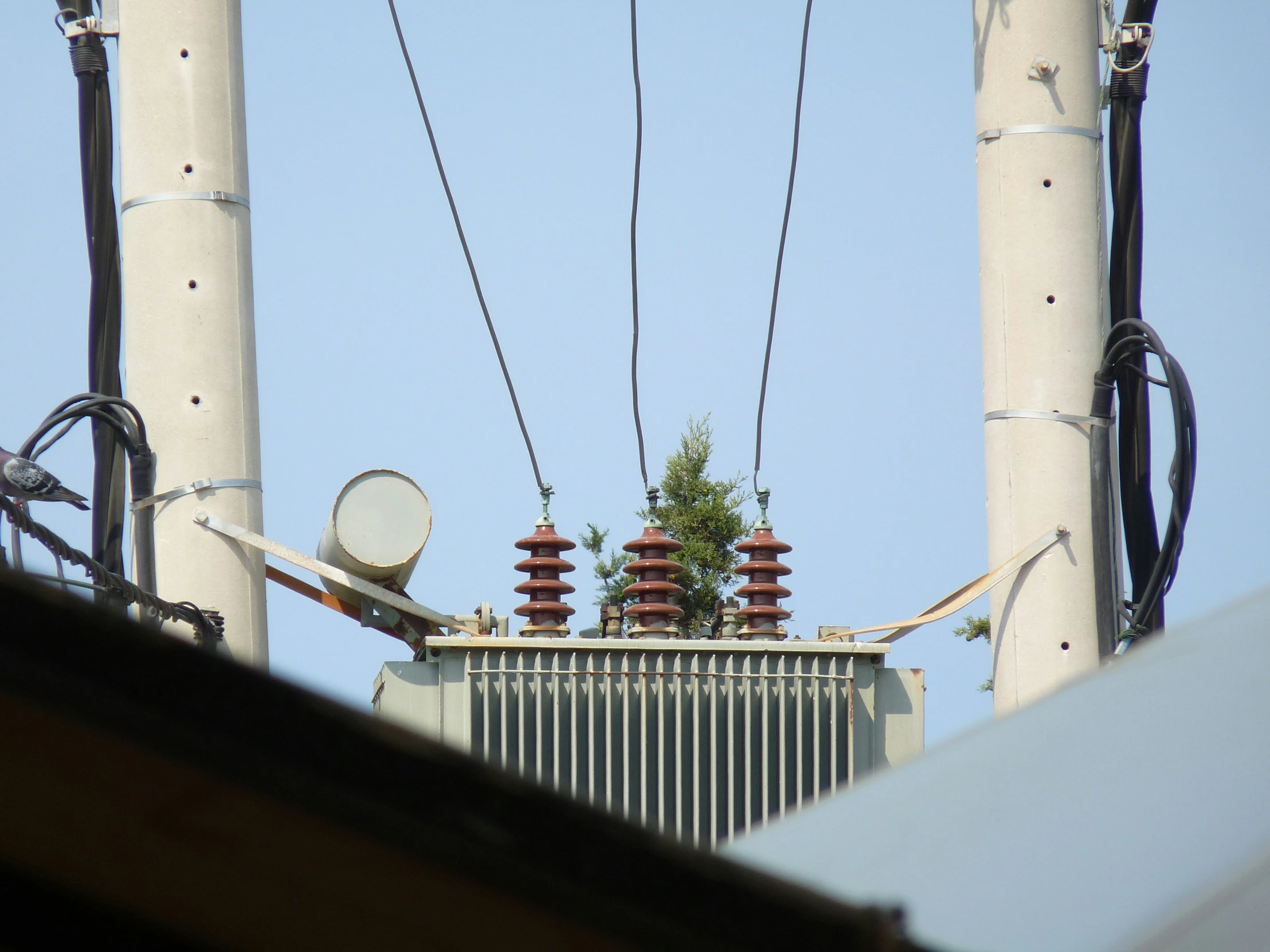 high voltage wires run through the air above a rooftop