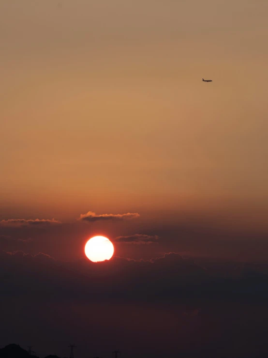 the setting sun with an airplane flying in the sky