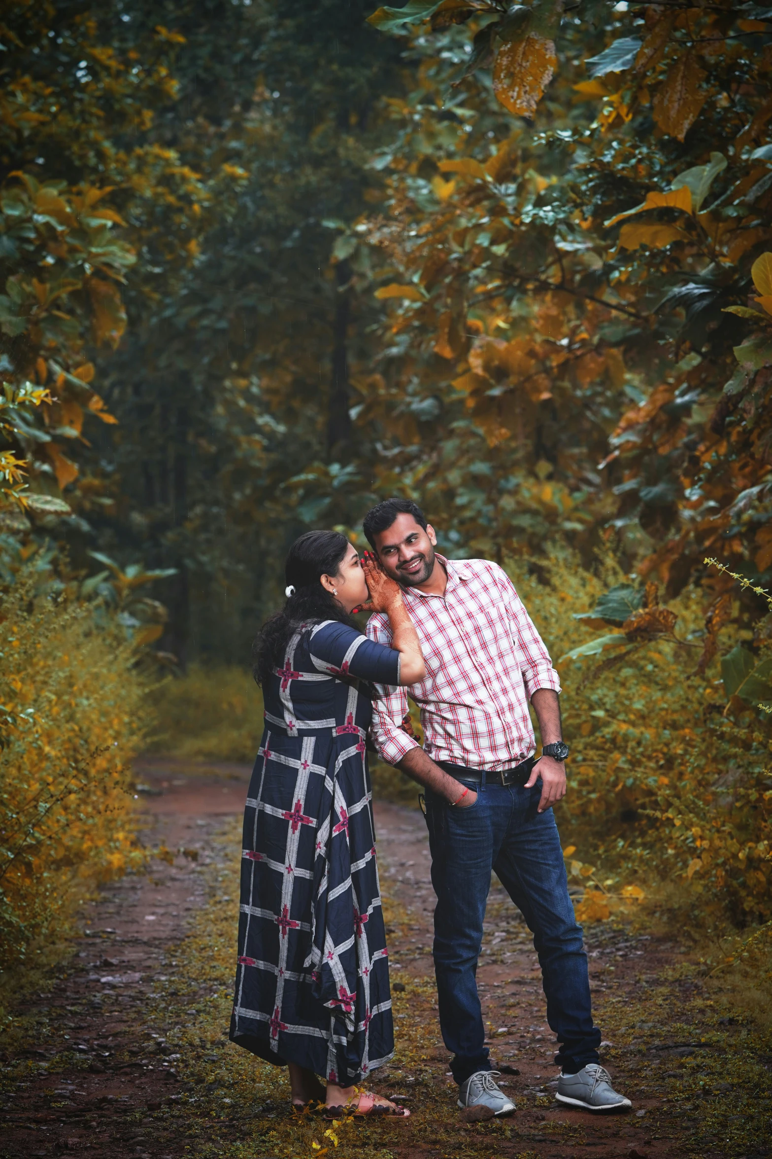 a woman kissing a man in front of trees