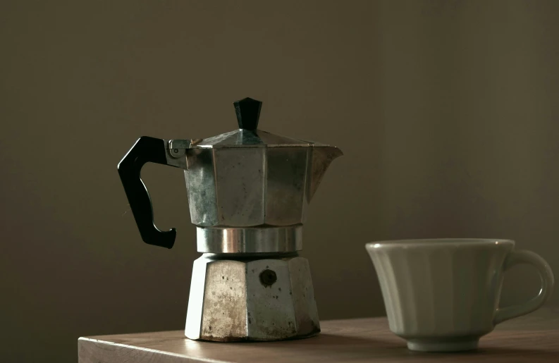 a metal stove top sitting next to a coffee cup