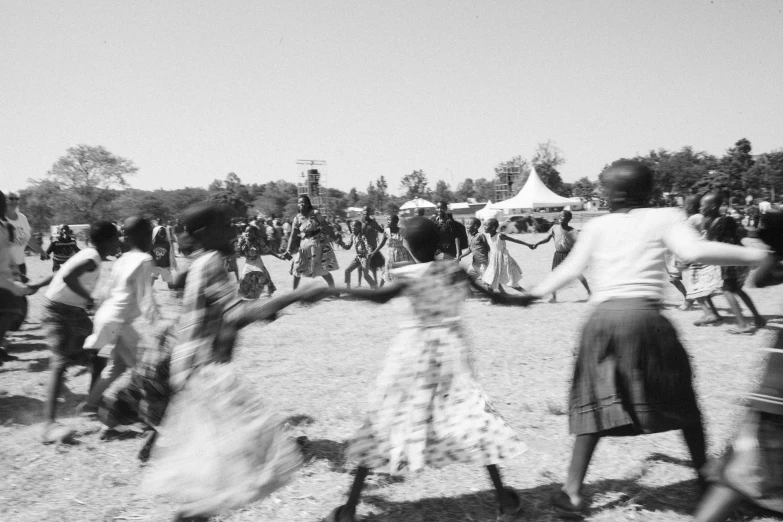 several people are dancing around outside on some dirt