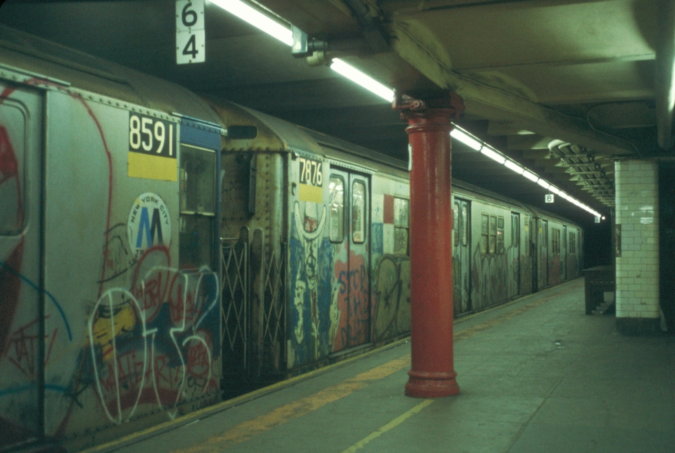 a subway station is covered with graffiti as it stands at its platform