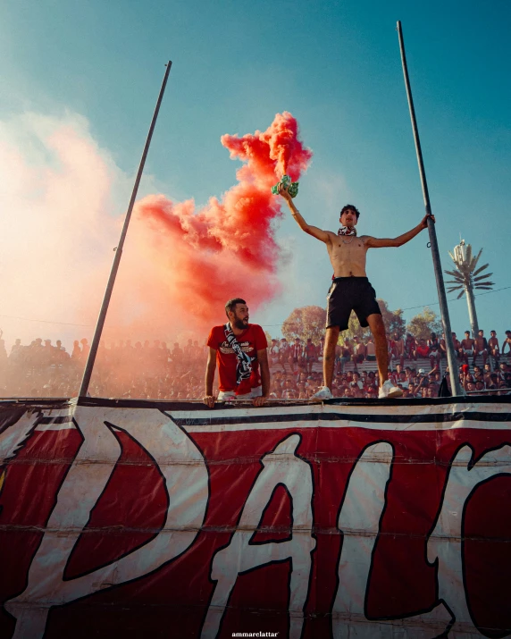 a man is on a street sign holding up smoke bombs