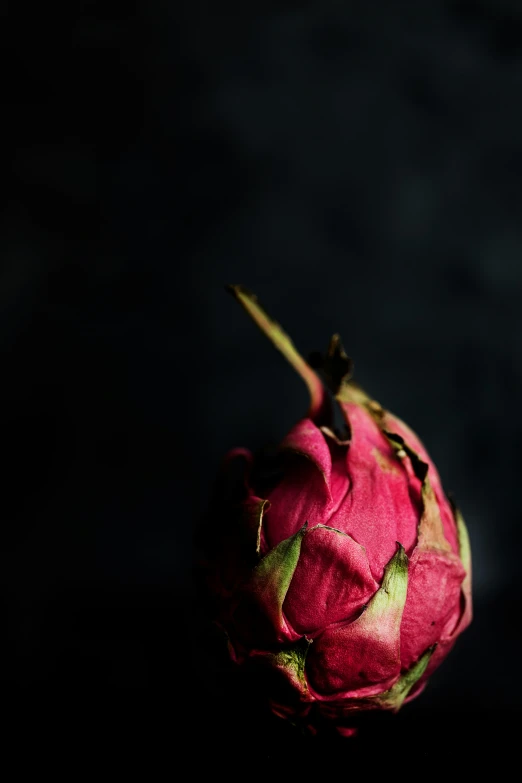 a very pretty, big pink piece of fruit on a black background