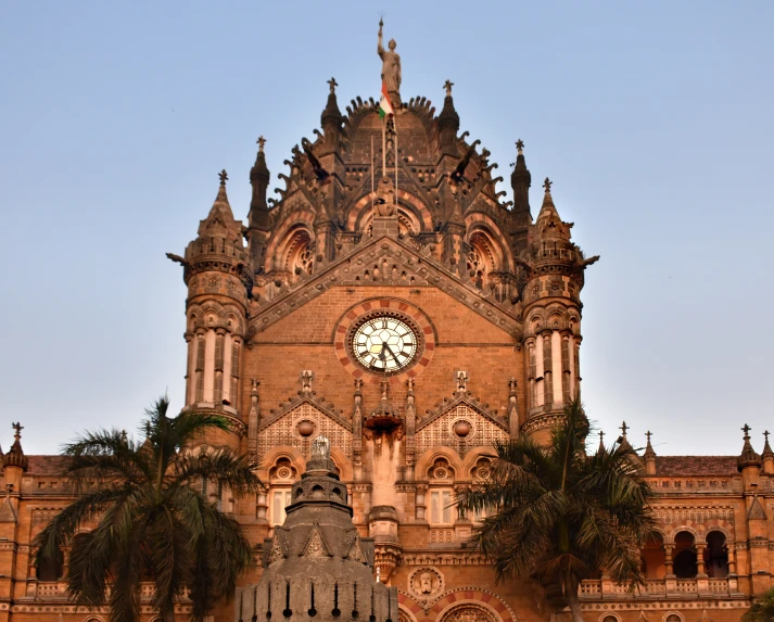 an ornate clock tower stands in front of palm trees