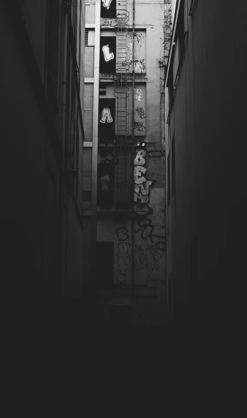 the dark alleyway leads to another building with graffiti written on it