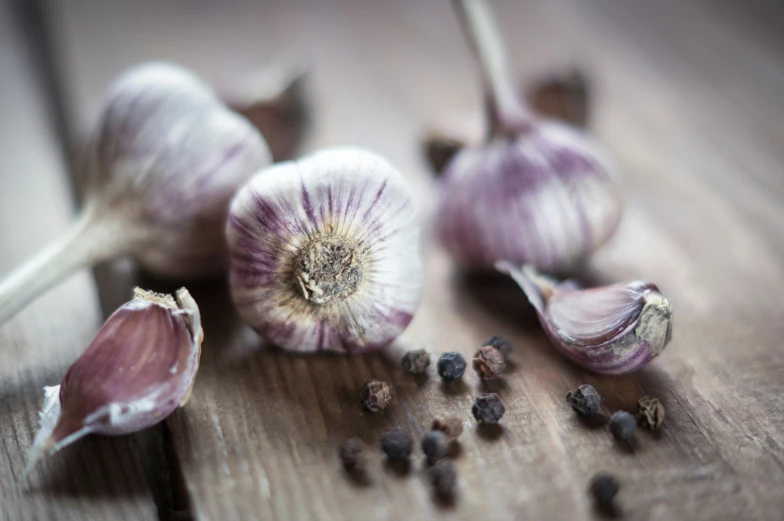 two bulbs of garlic sit on a wooden table