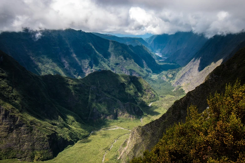 a valley surrounded by mountains under a cloudy sky