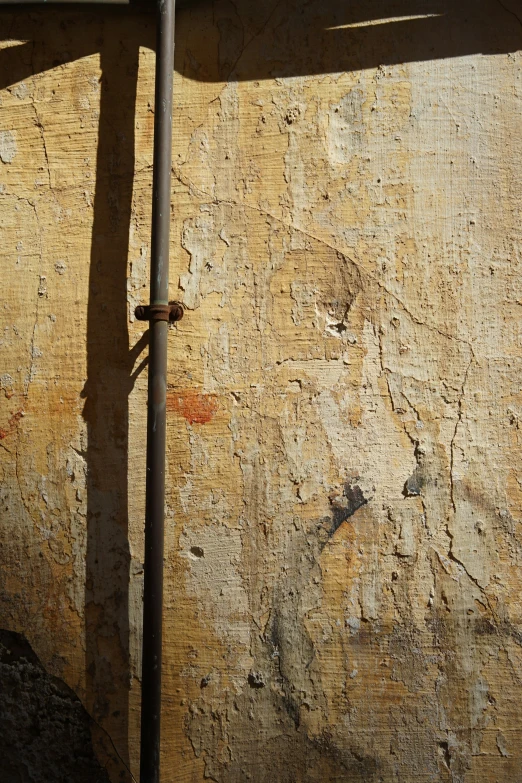 a brown wall with peeling paint, some rust on it