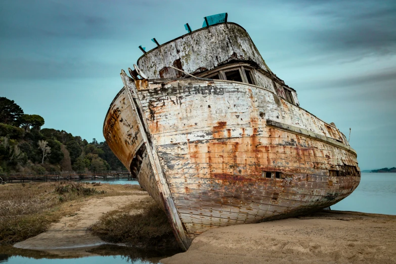 an old rusted up boat sitting on the shore