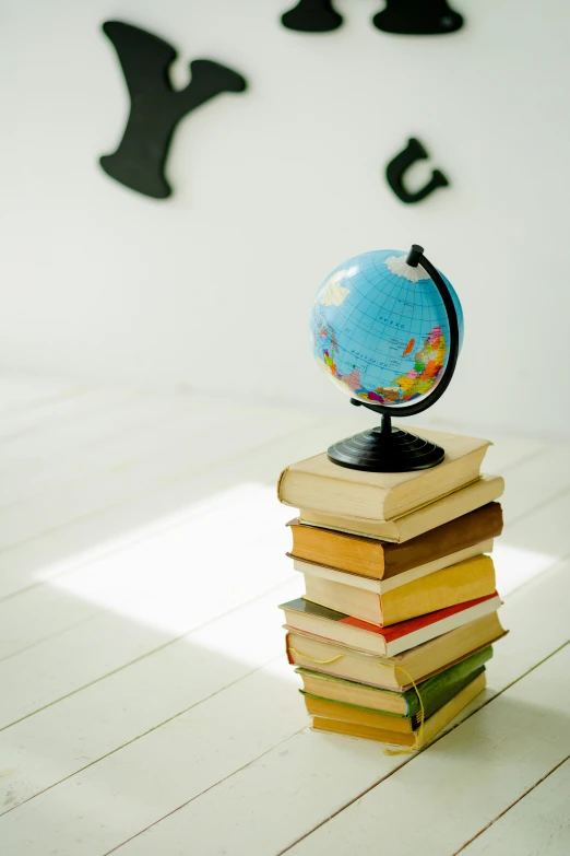 a stack of books with a globe on top of it