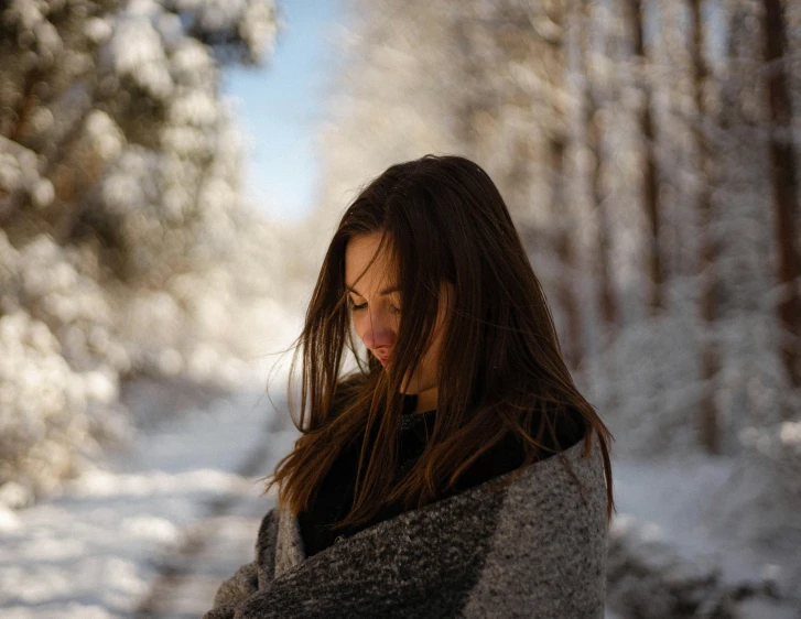 a woman stands in a snow covered path and looks away