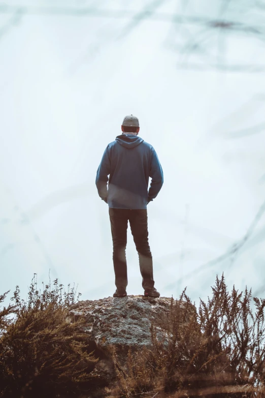 a man in blue coat standing on top of a small hill