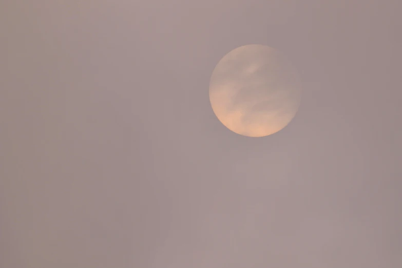 the sun in a distant sky with clouds and some birds in flight