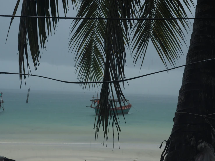 a boat sits on the shore of a tropical beach