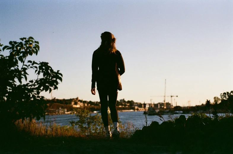 the person is standing in the grass looking at the water